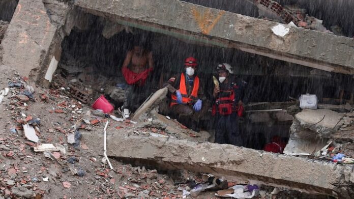 un-grupo-de-rescatistas-se-protege-de-la-lluvia-en-un-edificio-derrumbado-en-la-guaira-foto-reuters-E4V6NNZIE5GWLOPY7GI4DIQW74